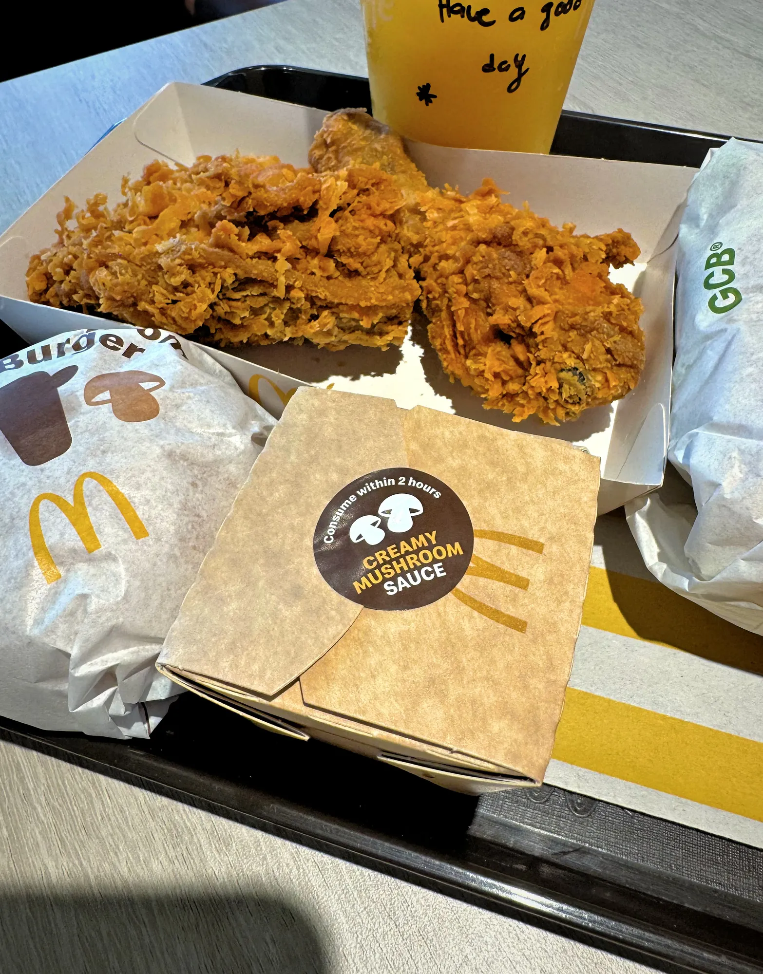 A close-up view of McDonald's Creamy Mushroom Sauce box, crispy Ayam Goreng chicken, and burgers on a dining tray in Kuala Lumpur.
