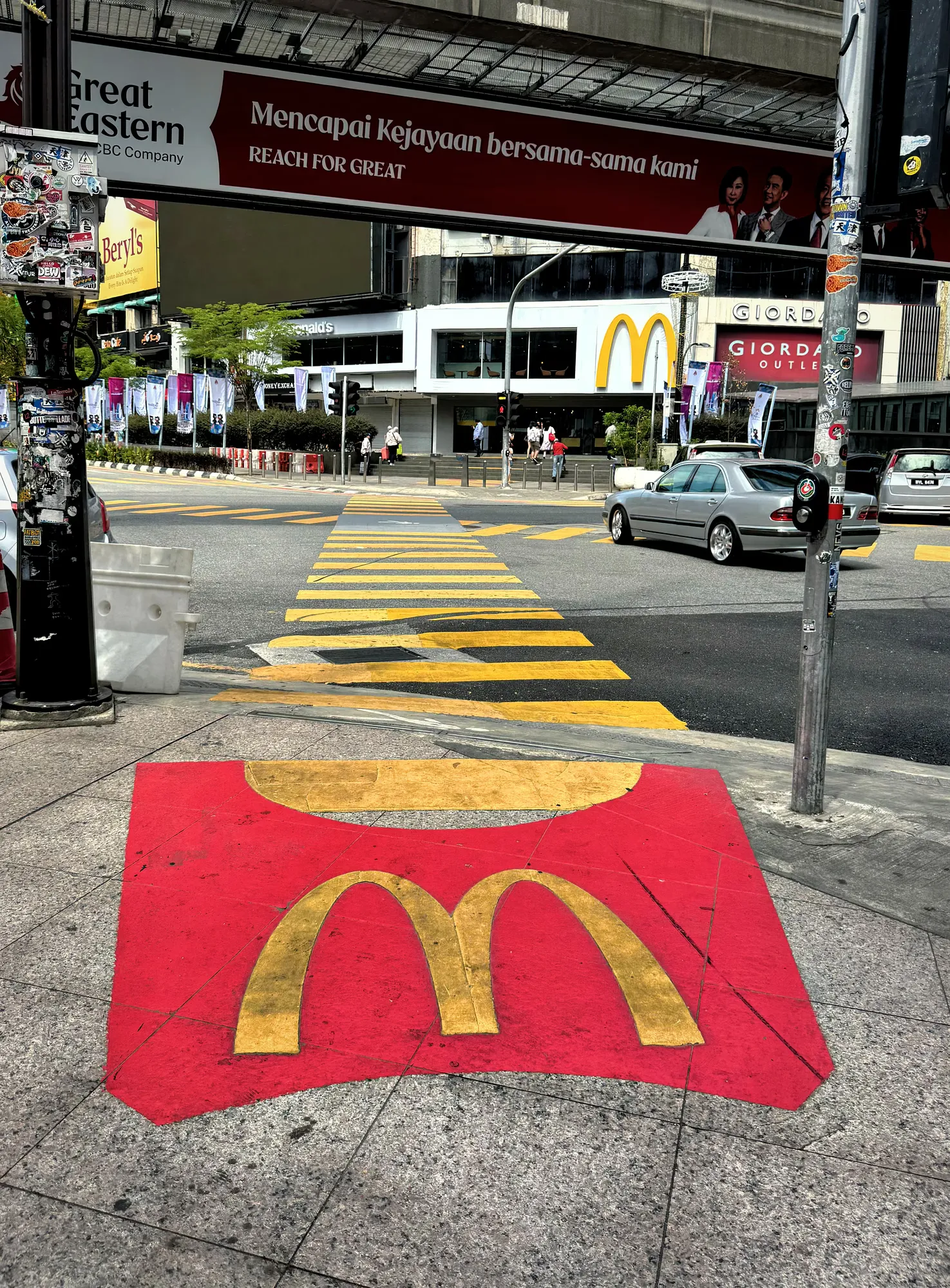 A painted McDonald's french fry container marks the sidewalk leading onto a crosswalk in Bukit Bintang, Kuala Lumpur.