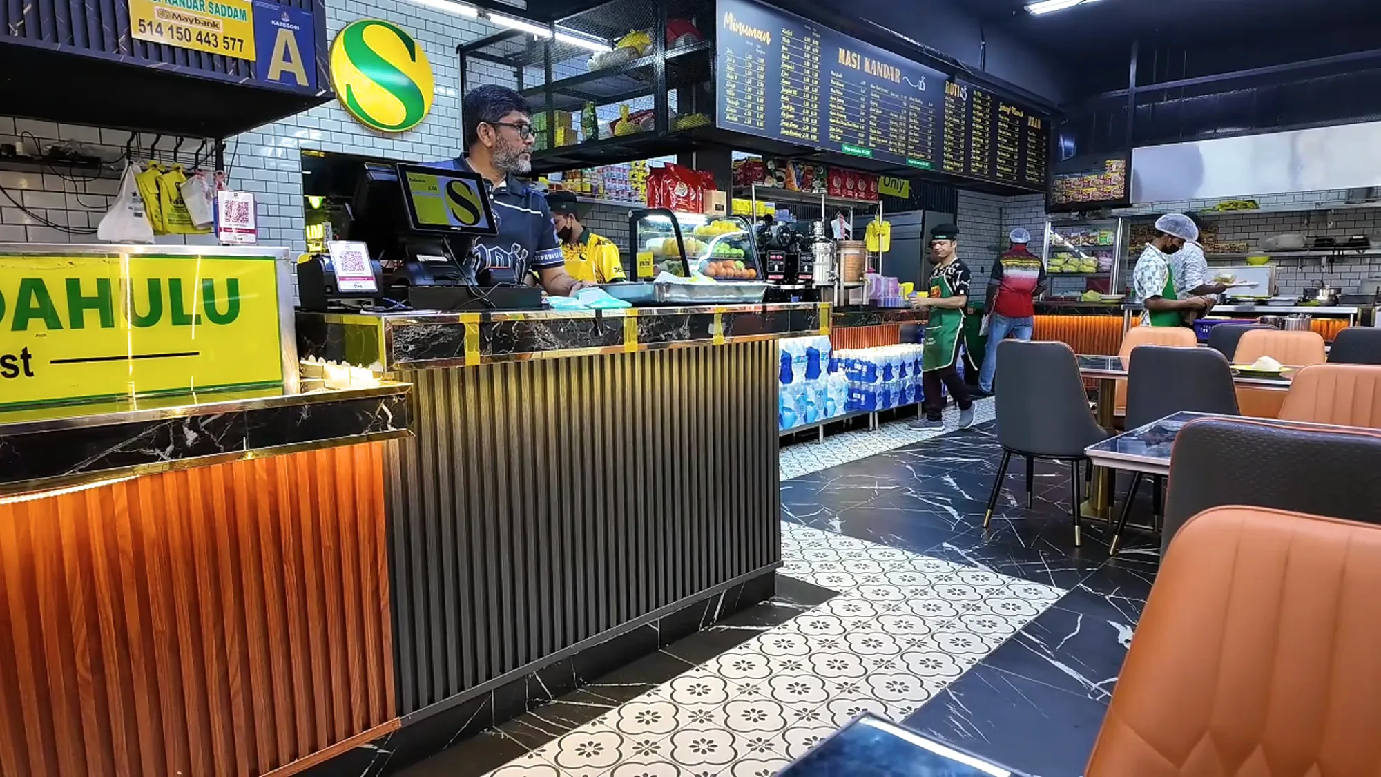 The cashier counter and patterned floor tiles inside Saddam Nasi Kandar, a cash-only nasi kandar restaurant in Kuala Lumpur.
