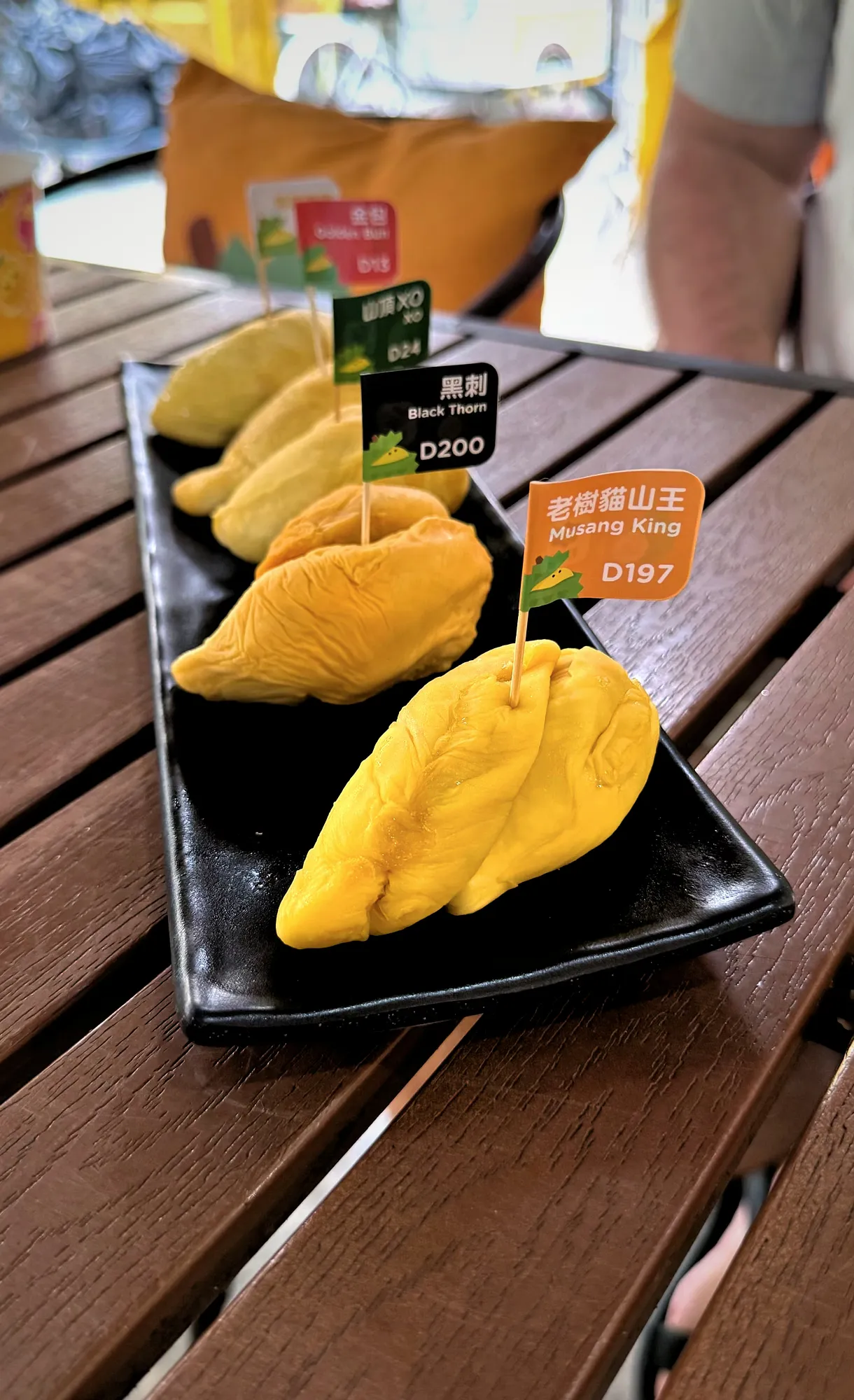 Musang King and Black Thorn durian on a black platter, with flags reading D197 and D200.