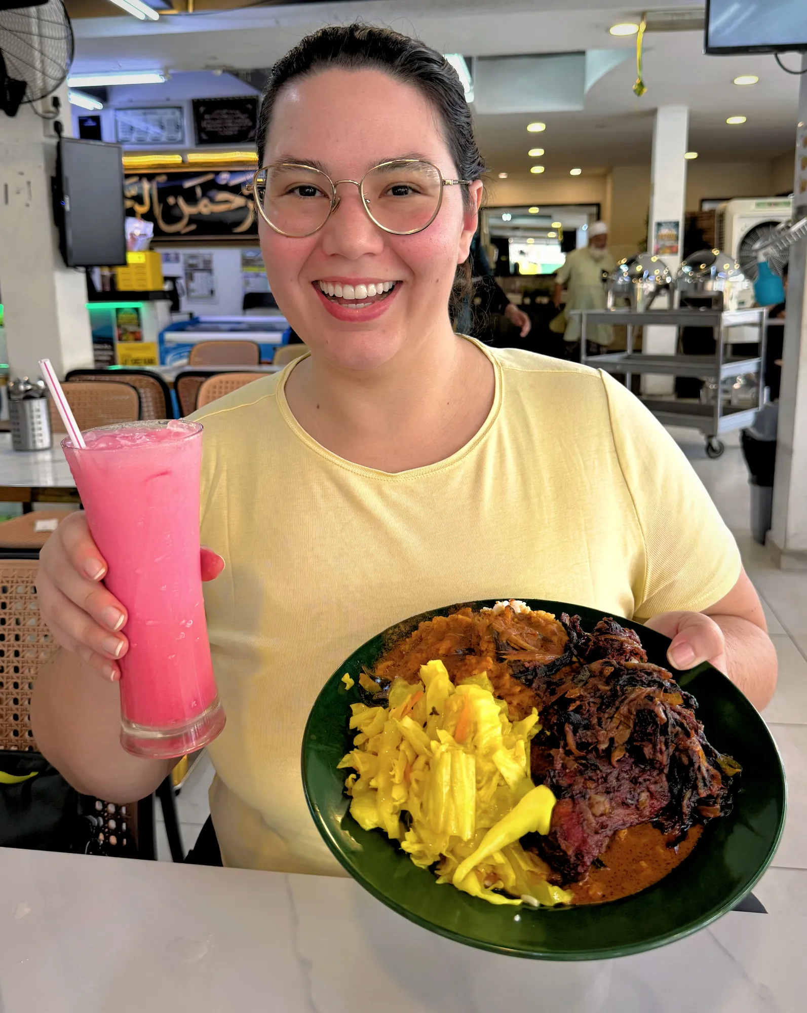 Holding up a plate of nasi kandar with dark fried chicken and cabbage next to a tall glass of pink sirap bandung at Line Clear in Kuala Lumpur