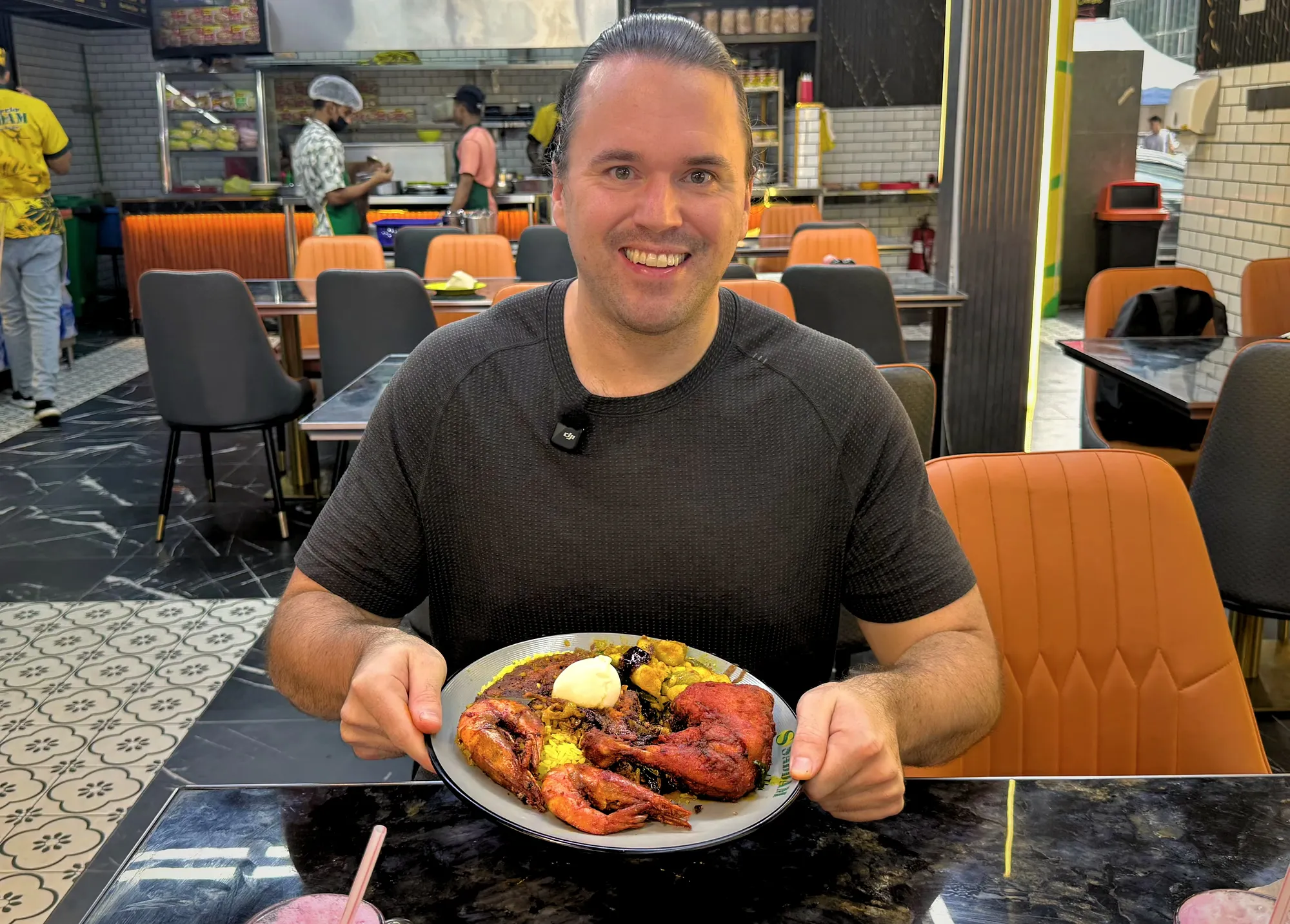 Holding a loaded plate of nasi kandar with fried chicken, tiger prawns, and curry inside Saddam Nasi Kandar in Kuala Lumpur