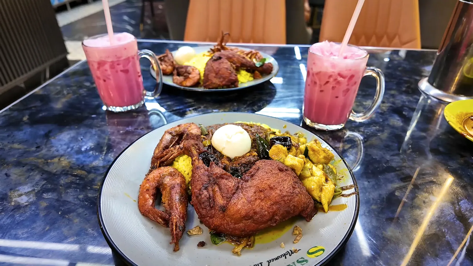 Cream smiling and holding a loaded plate of nasi kandar with fried chicken, tiger prawns, and curry inside Nasi Kandar Saddam in Kuala Lumpur.