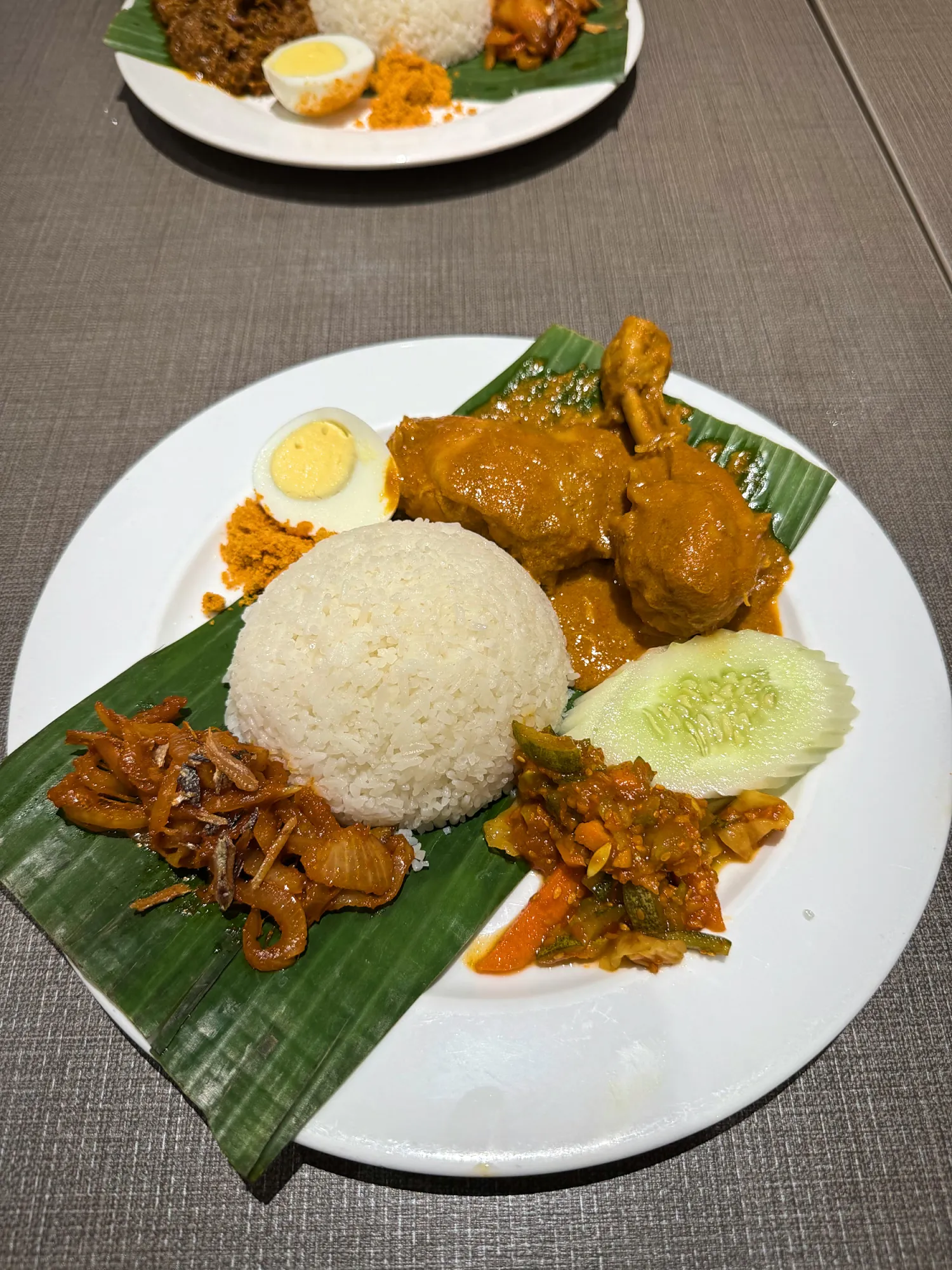 Nasi lemak with curry chicken, sambal, shrimp floss, pickled vegetables, cucumber, and an egg on a banana leaf at Madam Kwan's.
