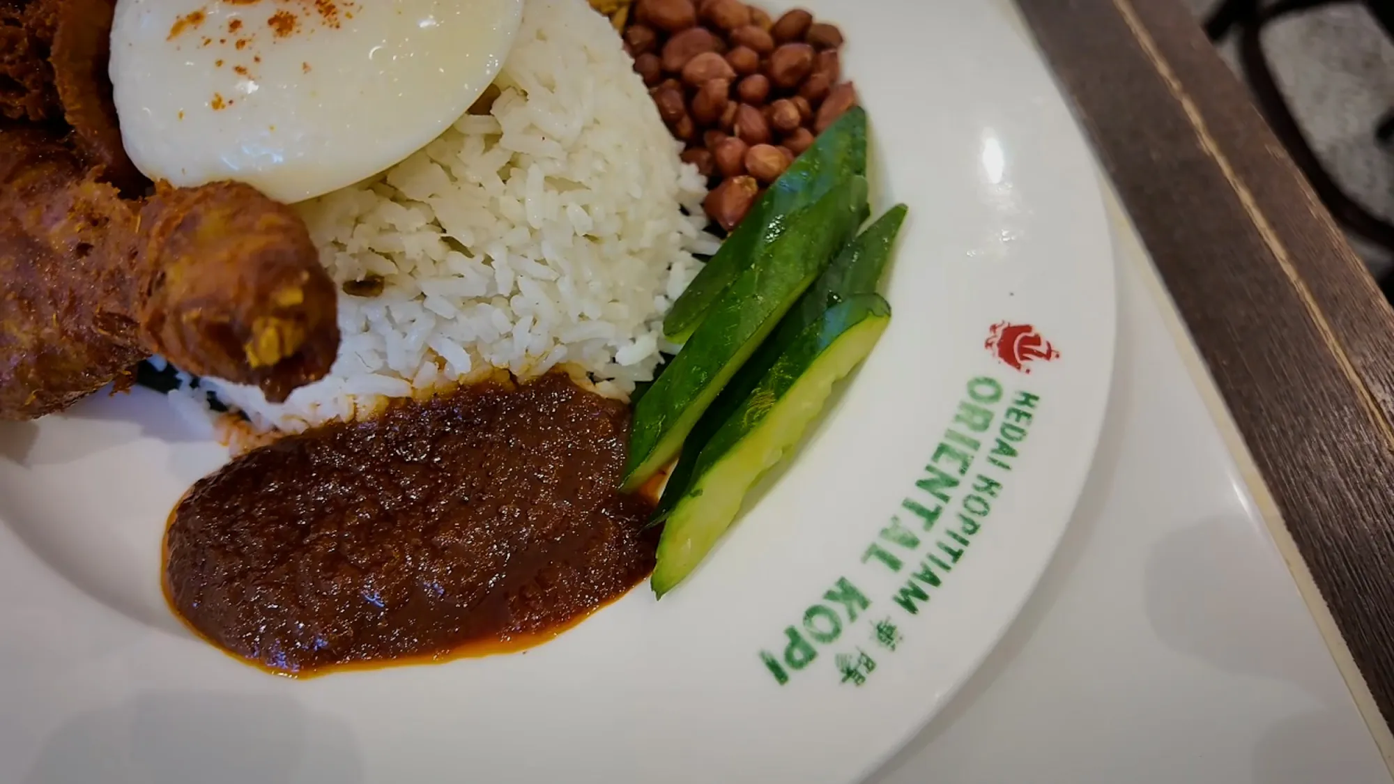 Oriental Kopi's nasi lemak up close: fried chicken, coconut rice, peanuts, cucumber, a fried egg, and smooth dark sambal