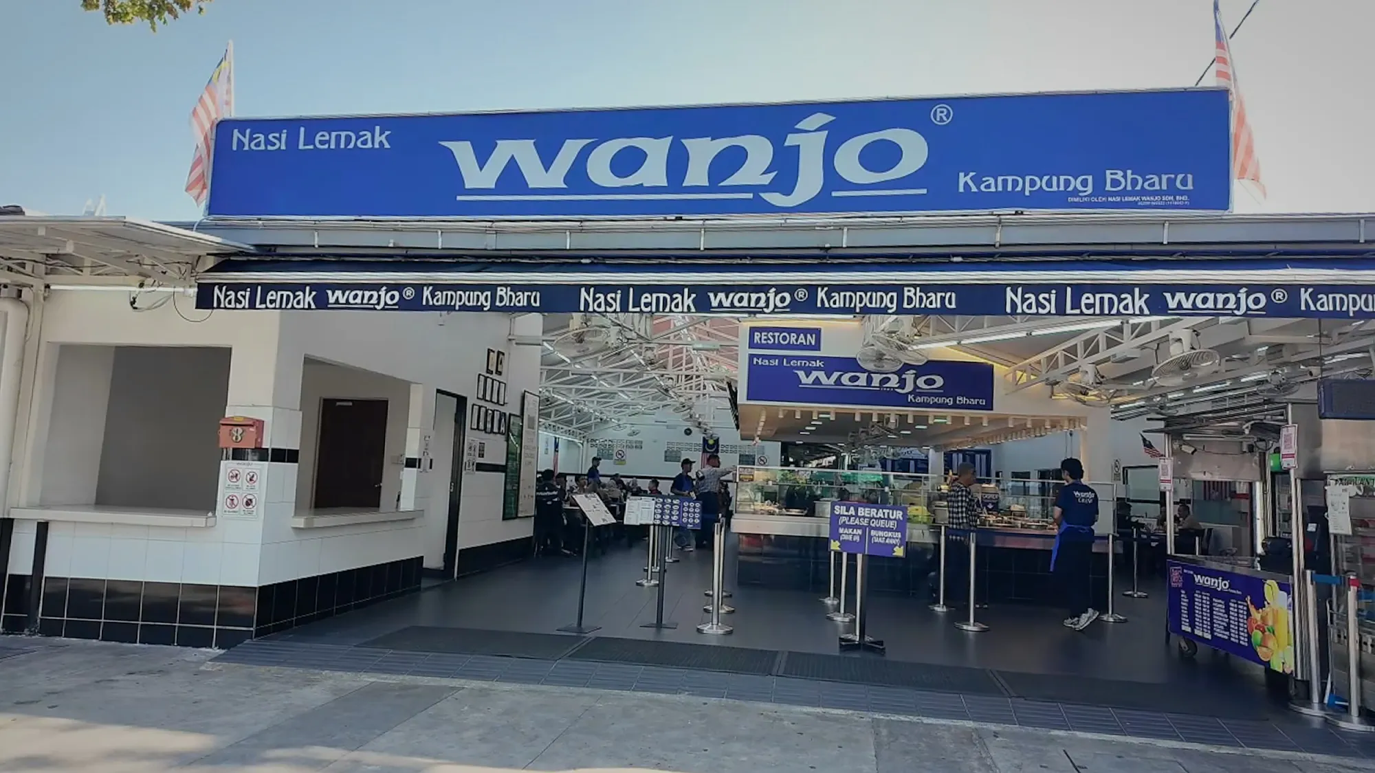 The blue Nasi Lemak Wanjo sign over the restaurant's open front in Kampung Baru, Kuala Lumpur