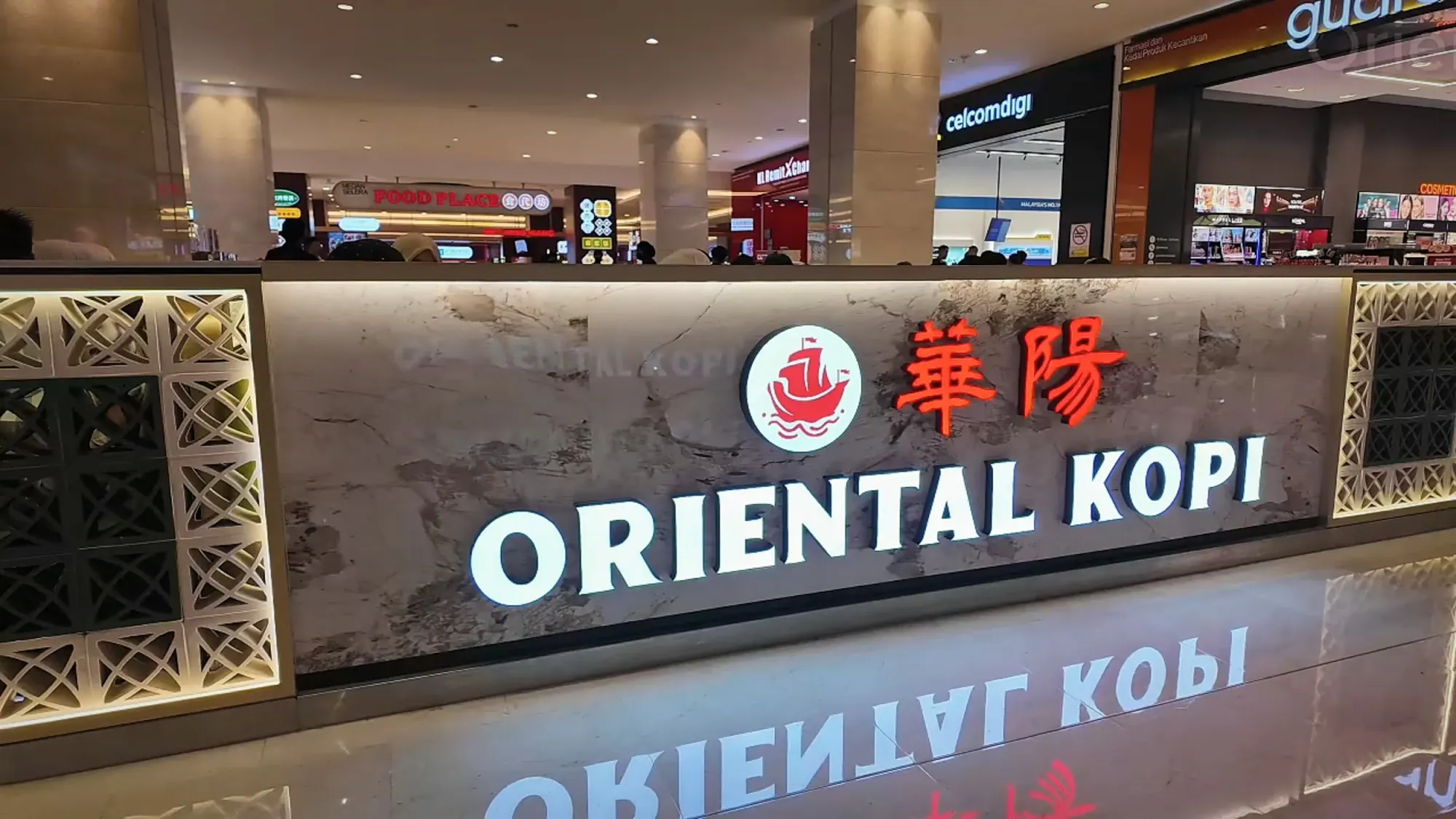 The illuminated Oriental Kopi sign with its red ship logo above the restaurant entrance in Pavilion Kuala Lumpur.