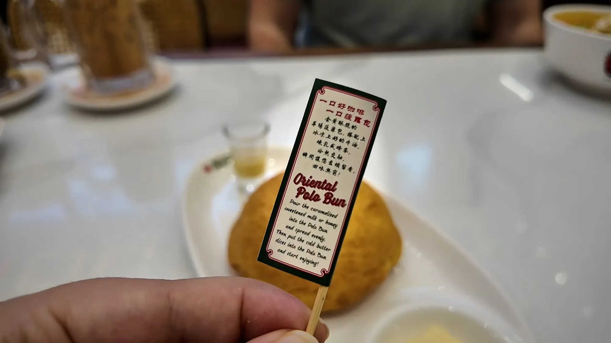 A hand holding the printed instruction card that comes with the Oriental Kopi polo bun.
