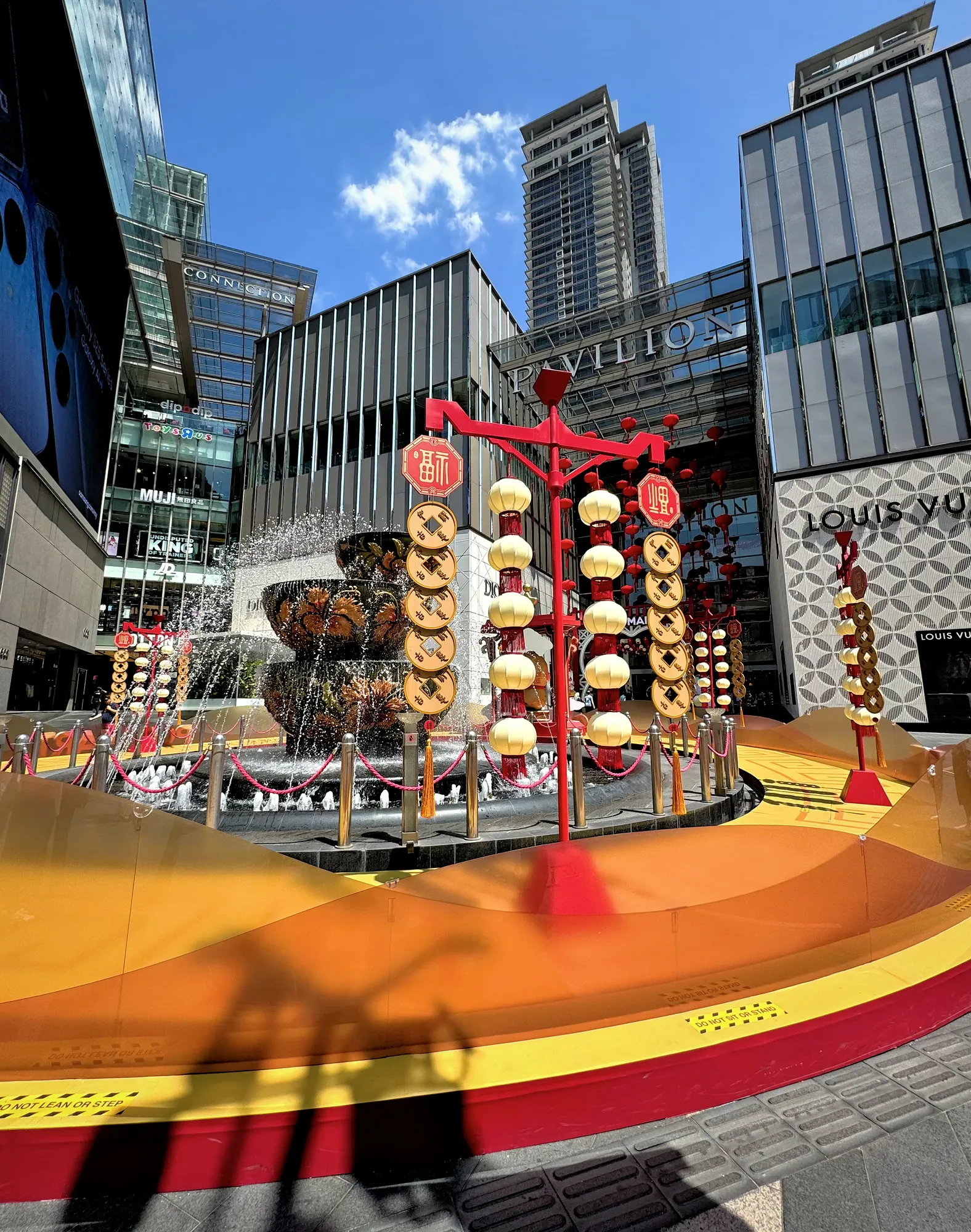 The tiered crystal fountain outside Pavilion Kuala Lumpur, framed by red and gold Chinese New Year decorations under a blue sky.
