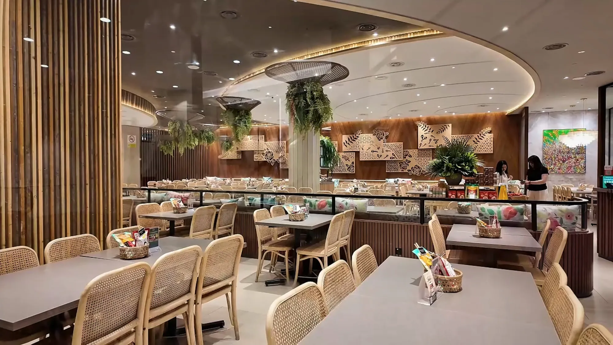 The empty dining room at Madam Kwan's in Pavilion Kuala Lumpur, with wooden chairs, a central counter, and hanging plants.