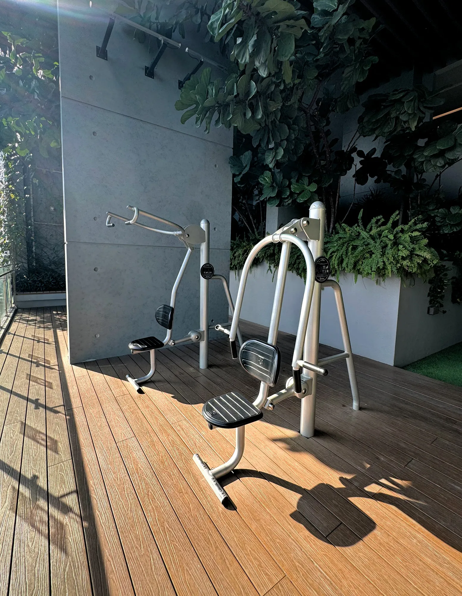 Outdoor exercise equipment on a timber deck surrounded by plants in a pocket garden at Ceylonz Suites.
