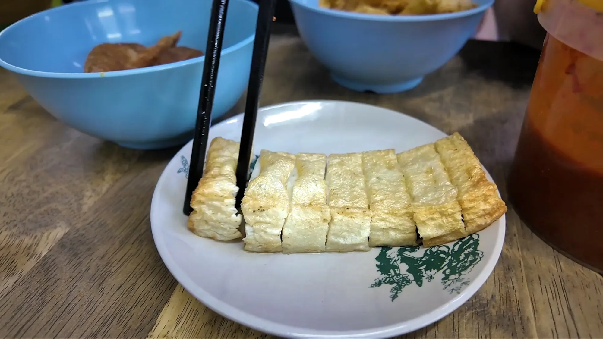 Picking up a slice of fishcake with chopsticks at Kin Kin chili pan mee.