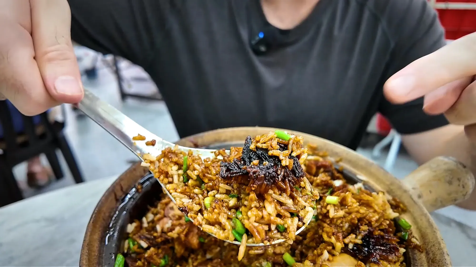 A spoonful of dark claypot chicken rice with crispy bits and spring onions lifted from the pot at 168 in Pudu.