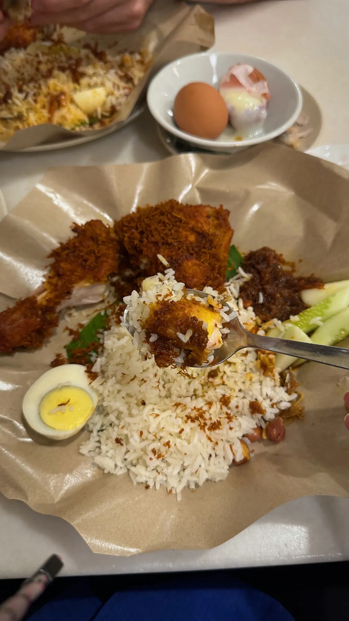 A spoonful of coconut rice and sambal lifted from a Village Park nasi lemak, with the fried chicken behind it