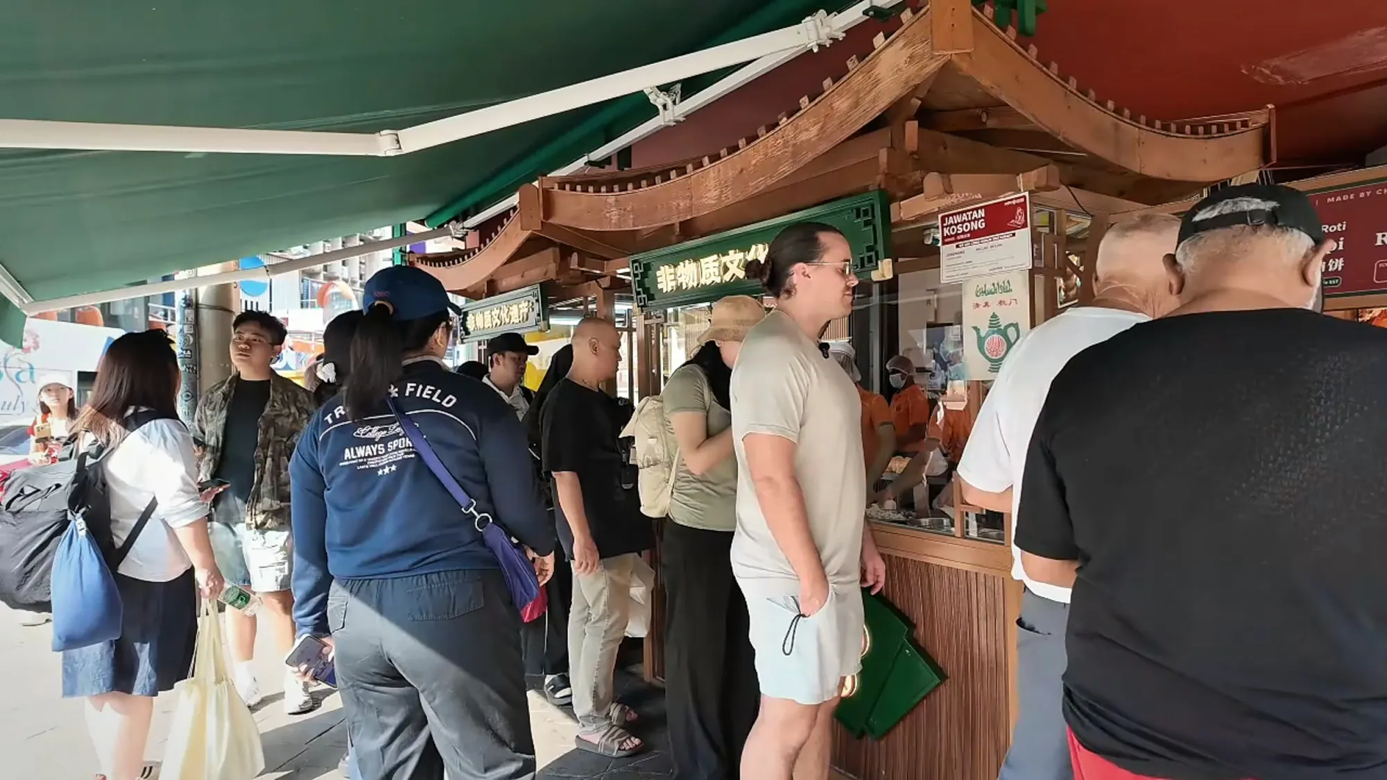 People queuing on the sidewalk at the Mon Chinese Beef Roti stall in Bukit Bintang, Kuala Lumpur.