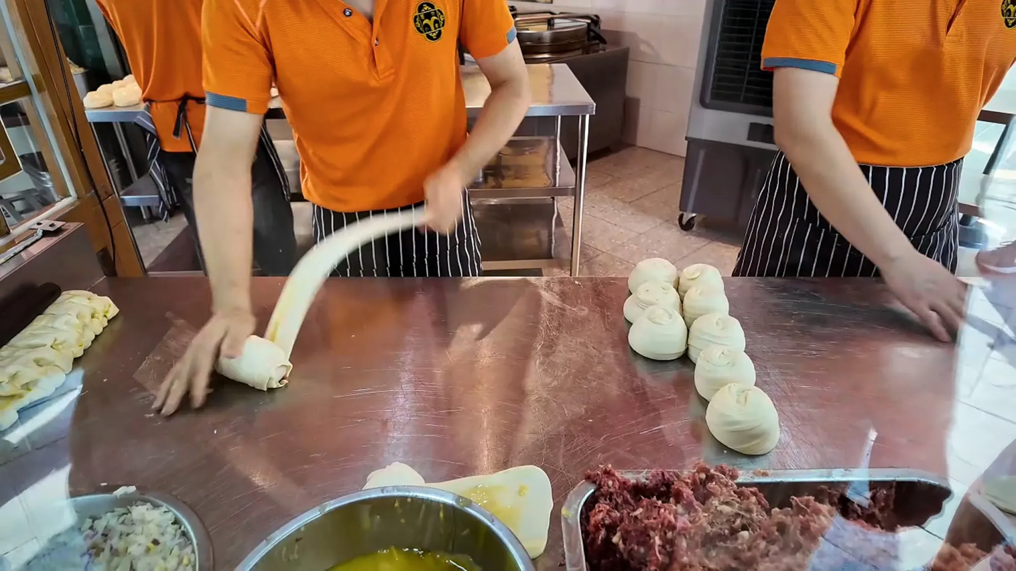 A cook stretching a long strand of dough at the Mon Chinese Beef Roti stall in Kuala Lumpur