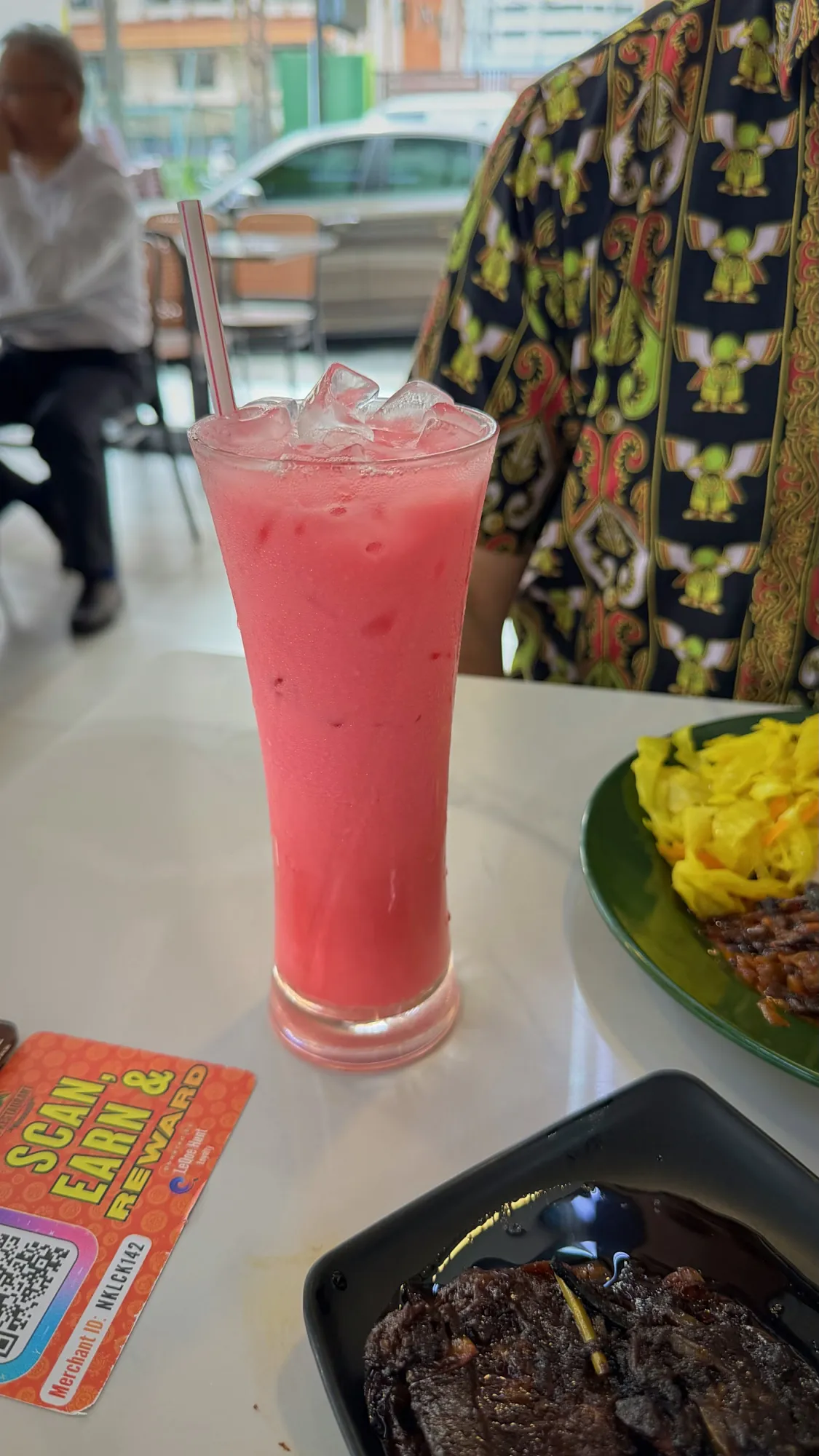A tall glass of iced pink sirap bandung with a straw on the table at Line Clear in Kampung Baru, Kuala Lumpur.