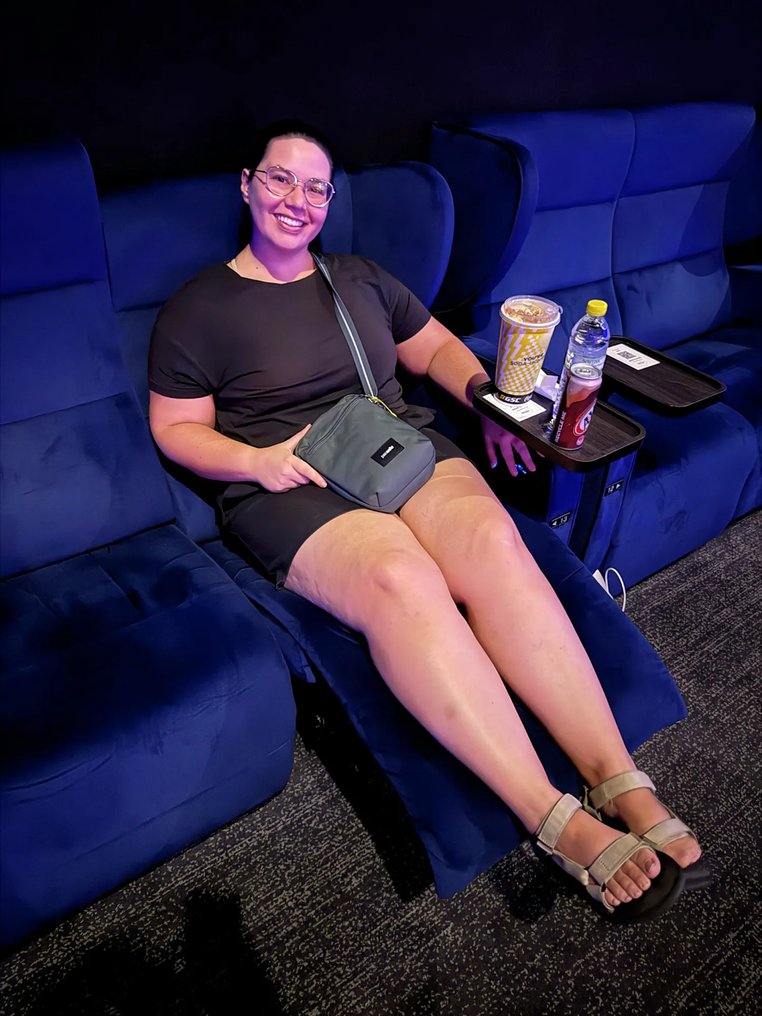 Bernie relaxing in a blue velvet IMAX recliner with popcorn and a bottle of water at Aurum Theatre, Kuala Lumpur.
