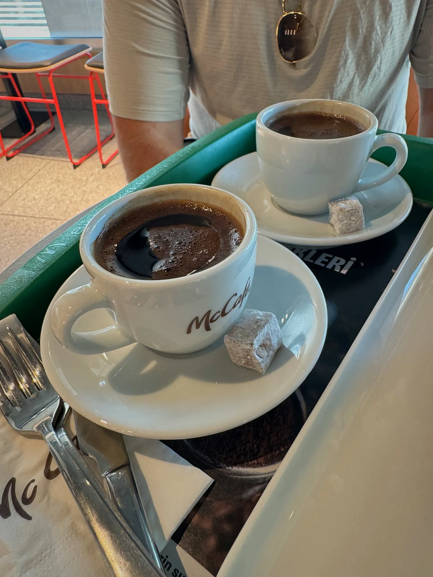A Turkish coffee in a white McCafé cup with a cube of Turkish delight on the saucer at McDonald's in Istanbul.
