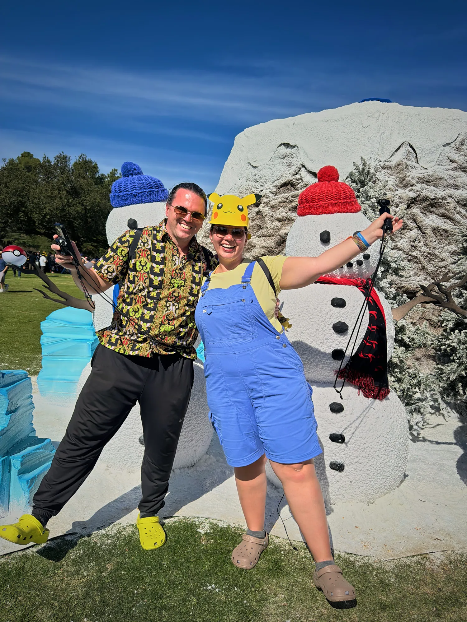 Bernie and Cream in Pikachu hats posing between two snowmen in knit hats at the winter habitat of Pokémon GO Tour Unova at the Rose Bowl.