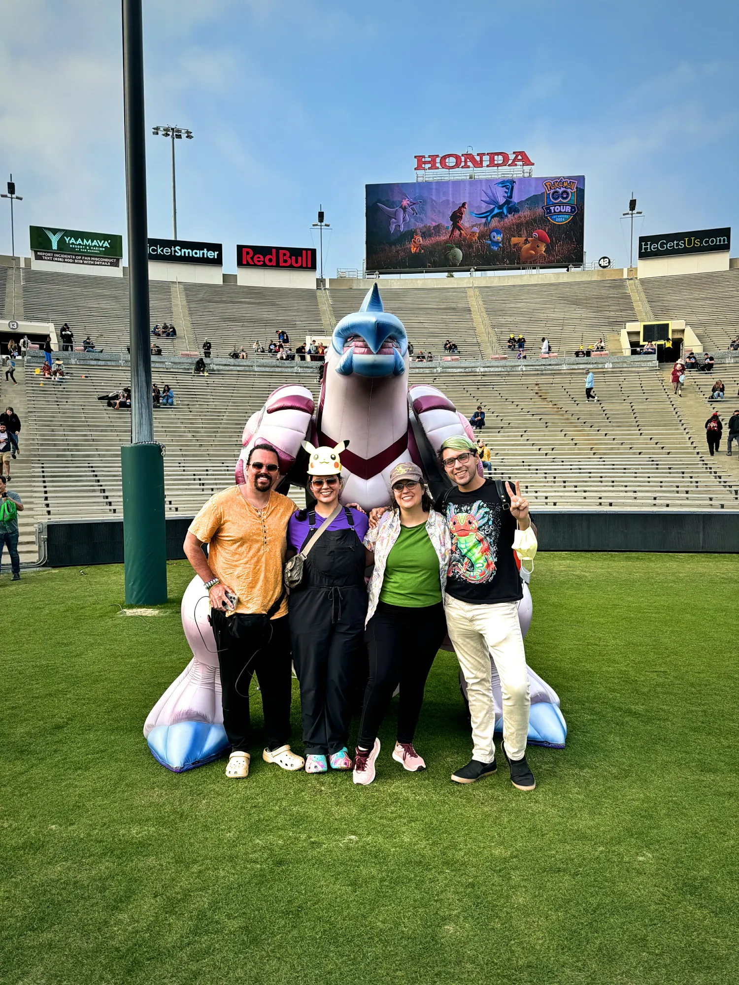 Bernie and Cream with two friends in front of a giant inflatable Origin Forme Palkia on the field inside the Rose Bowl during Pokémon GO Tour Sinnoh.