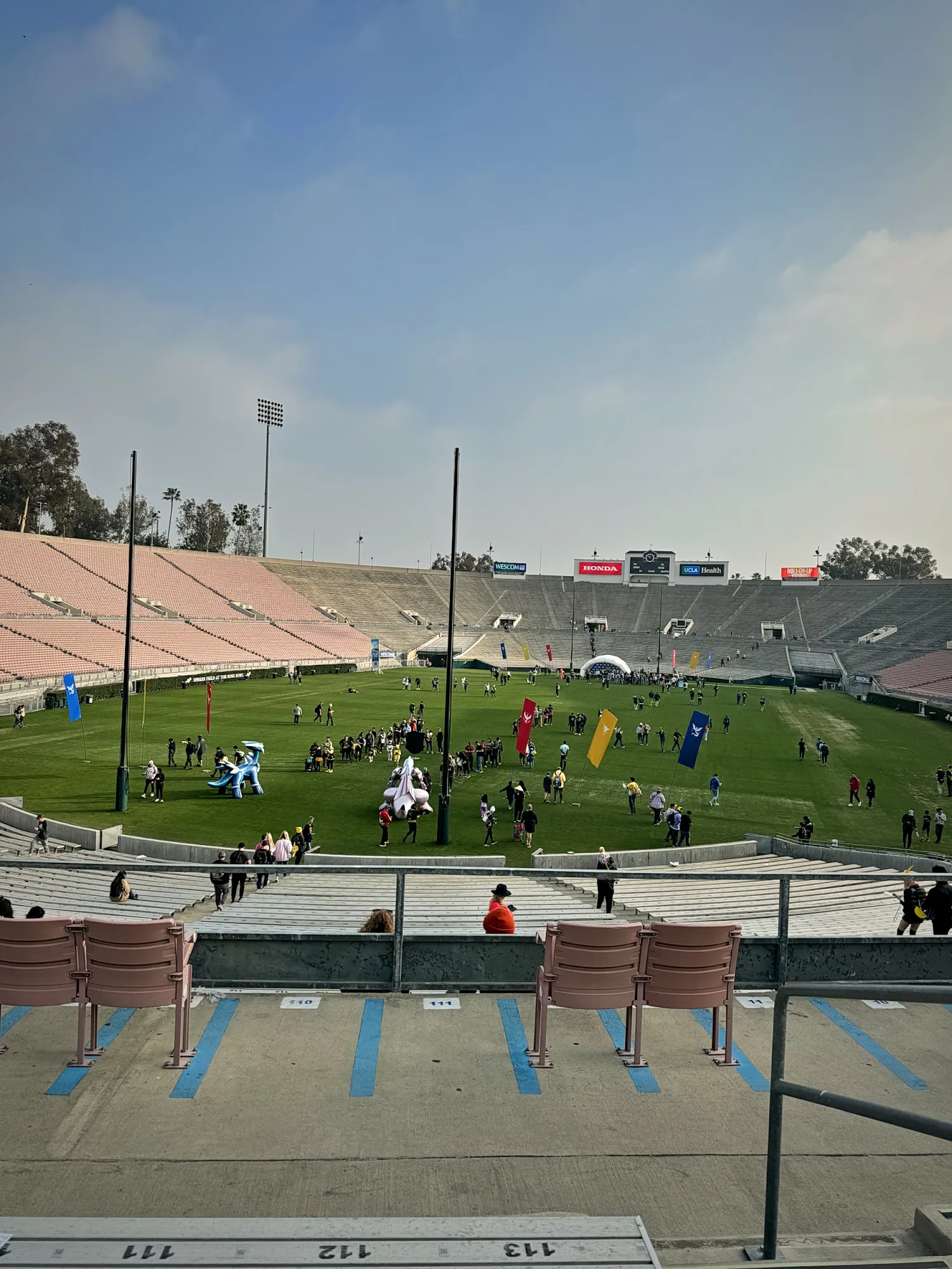 The open stands and grass field of the Rose Bowl during Pokémon GO Tour, with players on the field and no cover over the seats.