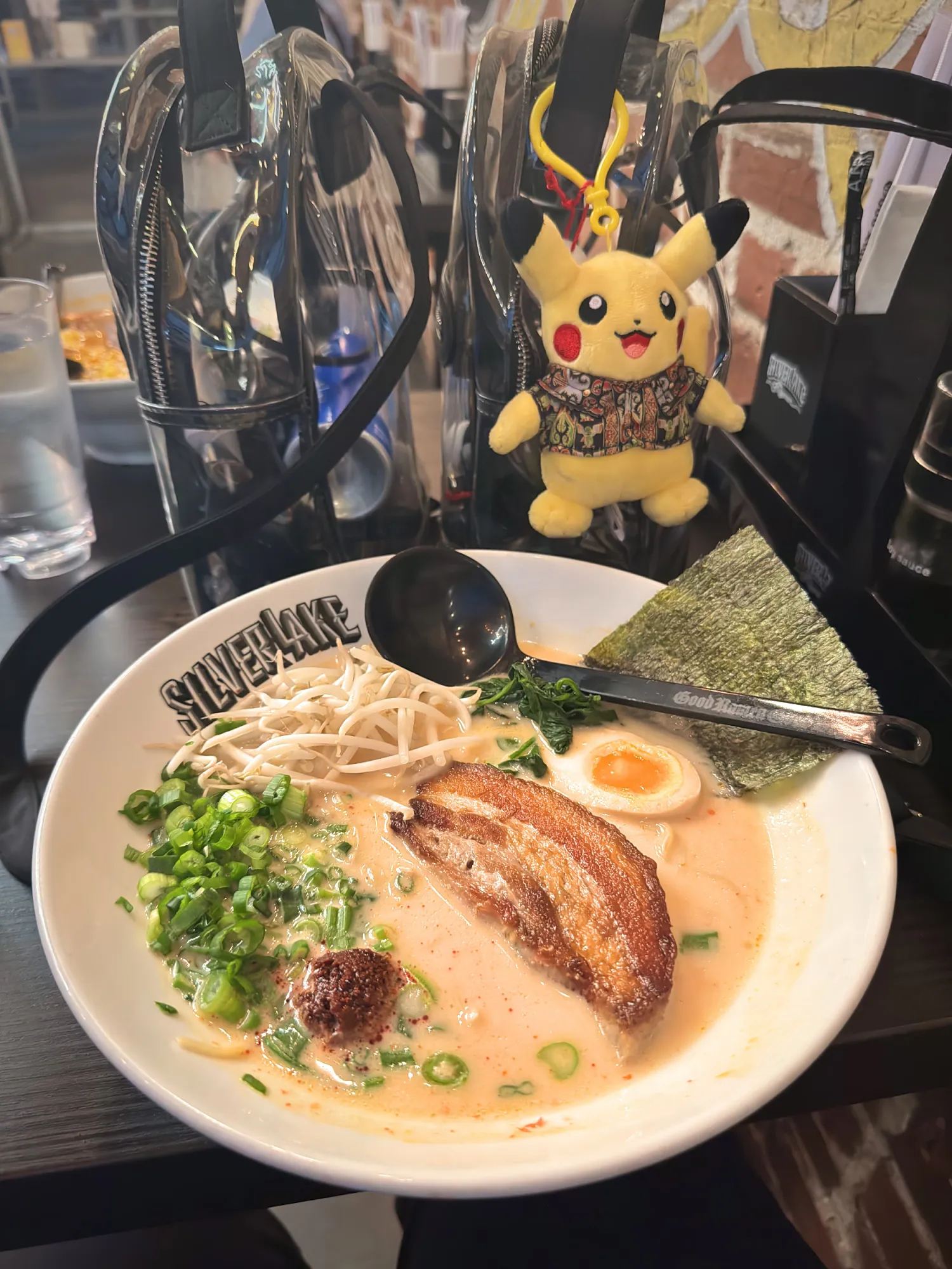 A bowl of tonkotsu ramen at Silverlake Ramen in Santa Monica, with a Pikachu plush in a Hawaiian shirt clipped to a clear bag behind it.