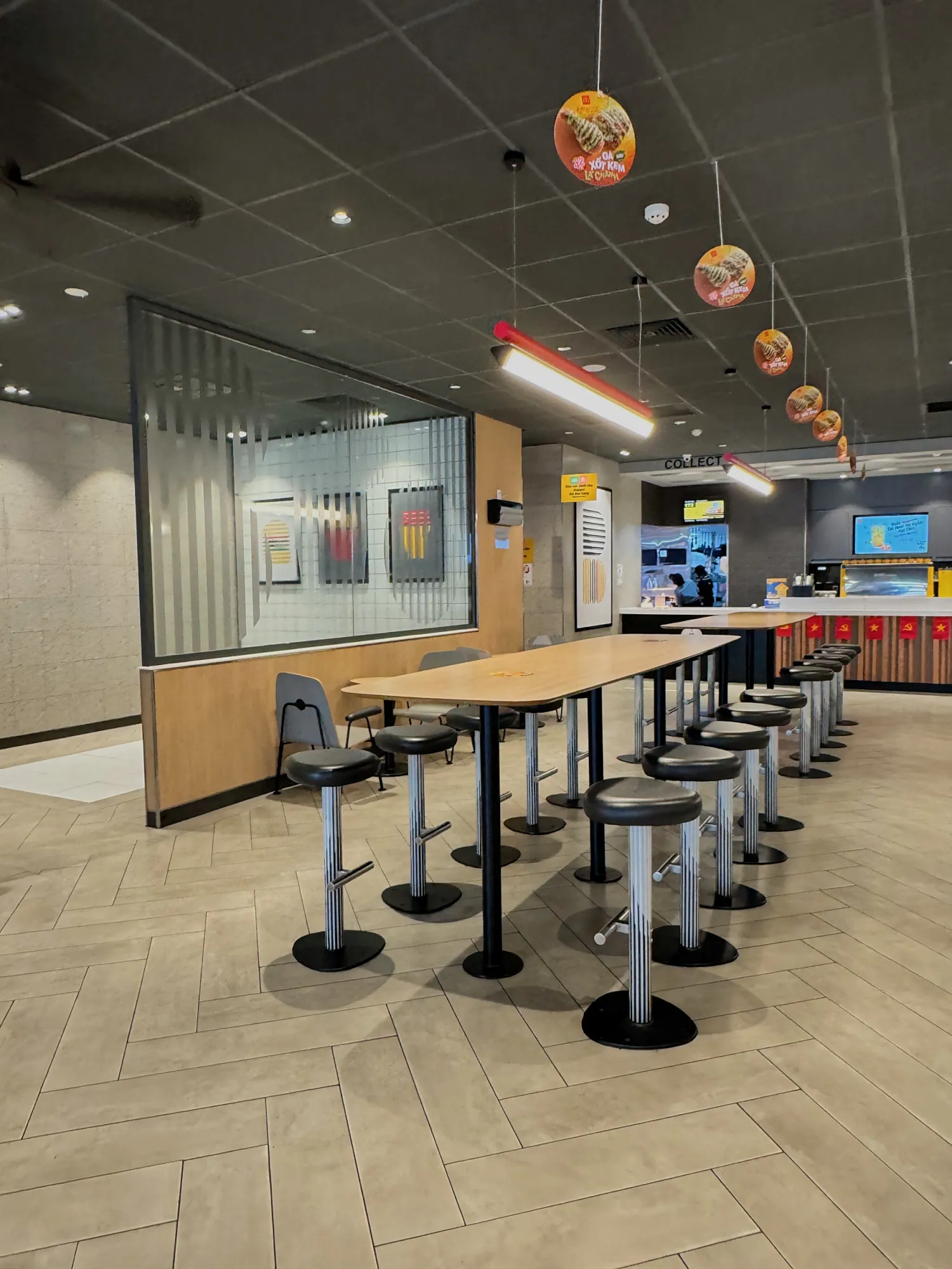 The bright, modern seating area of a McDonald's in Da Nang, Vietnam, with long wooden tables and stools.